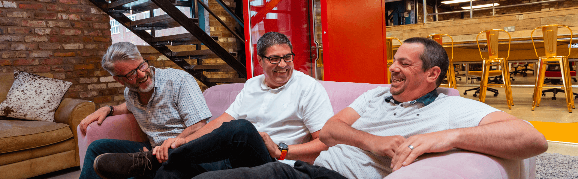 Axon IT team laughing together on a sofa in the office